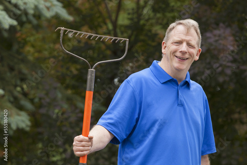 Man with Cerebral Palsy and dyslexia holding his rake