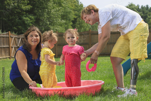 Grandmother with a prosthetic leg playing with her grandchildren on a child's pool photo