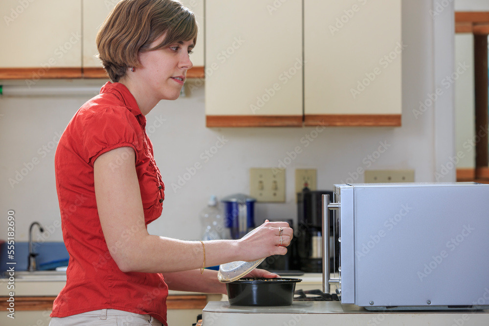 Young blind woman cooking in her kitchen with her microwave Young blind woman cooking in her kitchen with her microwave