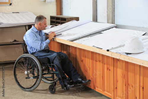 Project engineer with a Spinal Cord Injury in a wheelchair using a tablet to study drawings photo