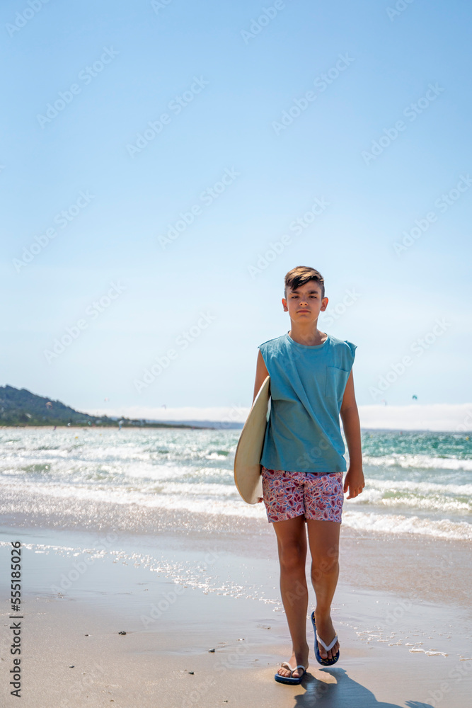 Dark-haired boy surfing with his skinboard on a beach Dark-haired boy surfing with his skinboard on a beach