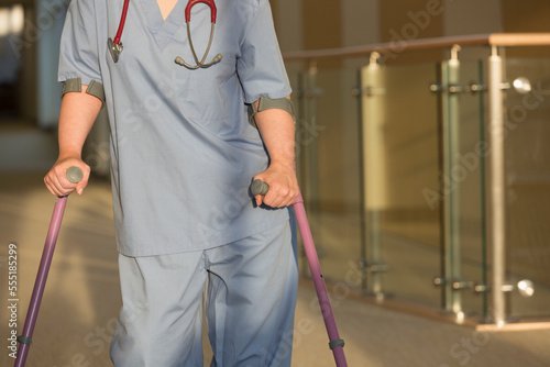 Nurse with Cerebral Palsy walking down the hallway of a clinic with her canes photo