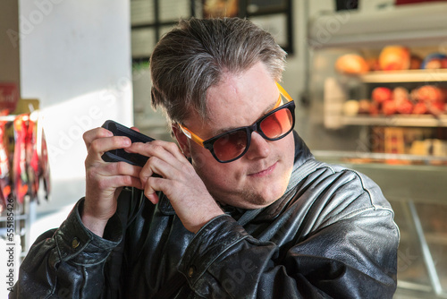 Man with congenital blindness using  assistive technology to listen at the market photo