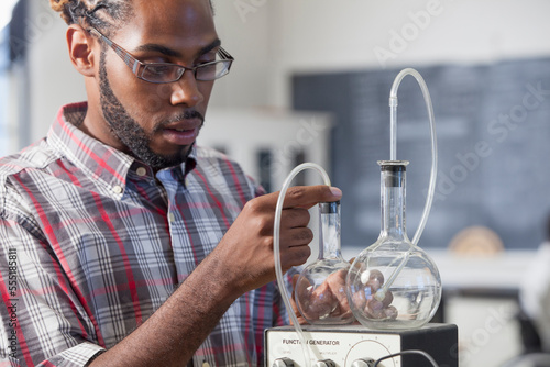 Student who had Spinal Meningitis setting up flasks for a volume versus pressure experiment in laboratory photo