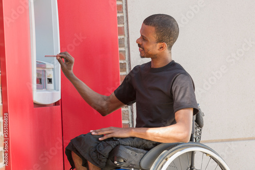 Man in a wheelchair who had Spinal Meningitis using a bank ATM photo