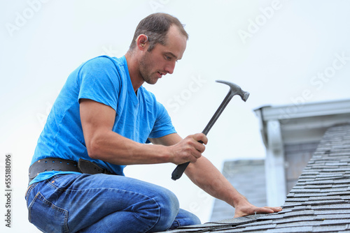Roofer with hearing aid on his ear working on the new roof photo