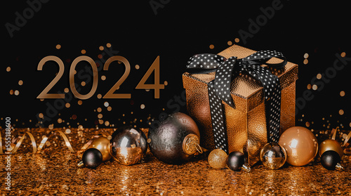 Happy New Year 2024! Golden gift box and christmas balls on golden background