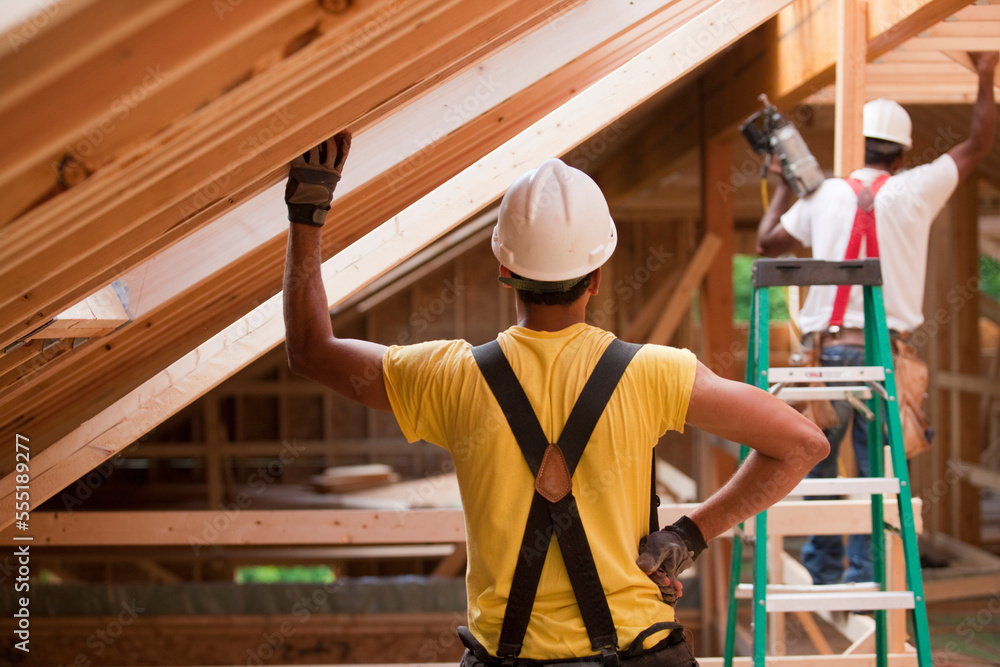 Hispanic carpenters working on roof beams at a house under construction Hispanic carpenters working on roof beams at a house under construction