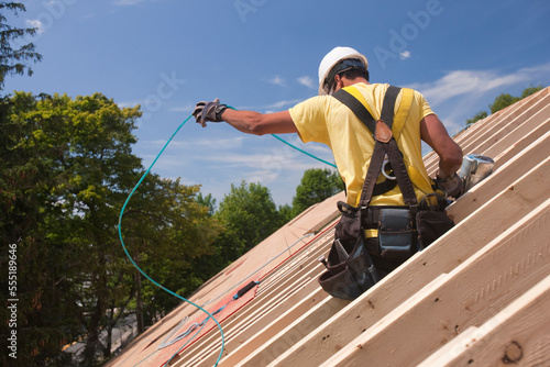 Hispanic carpenter untangling air hose at a house under construction photo