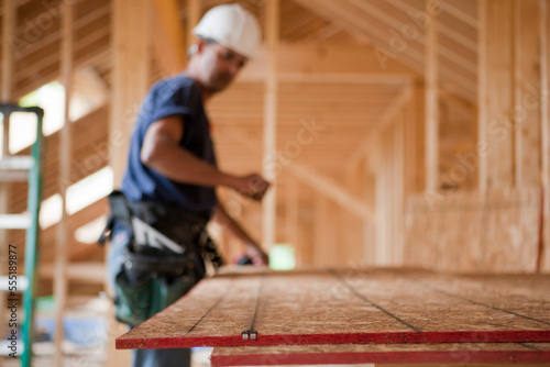 Hispanic carpenter snapping a string line on a roof panel at a house under construction photo