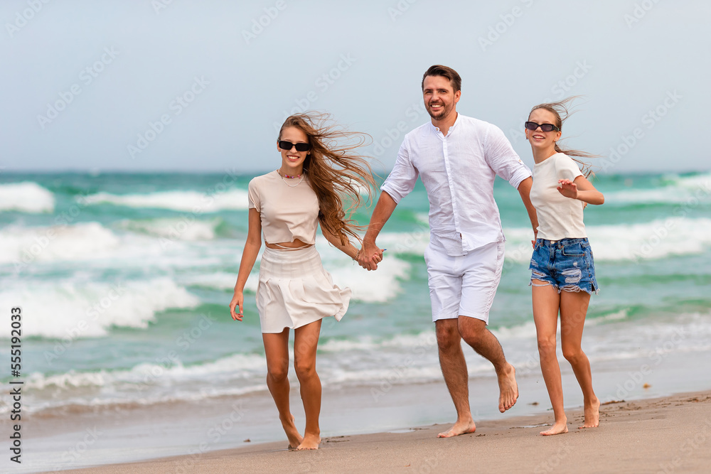 Happy father and adorable little kids on tropical beach having fun. Family vacation Happy father and adorable little kids on tropical beach having fun. Family vacation
