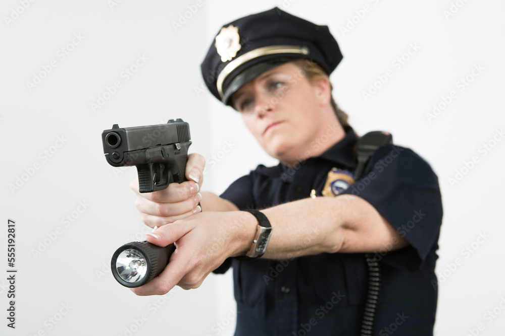 Police woman pointing handgun and holding flashlight. Police woman pointing handgun and holding flashlight.