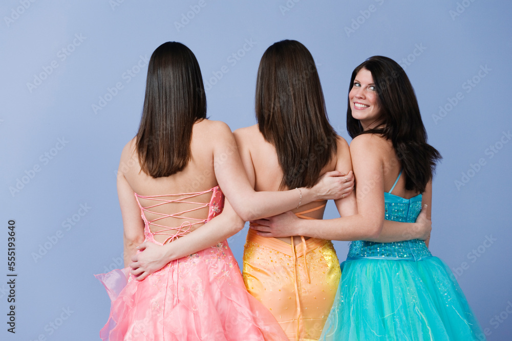 View of friends holding each other by the waist wearing prom dresses. View of friends holding each other by the waist wearing prom dresses.