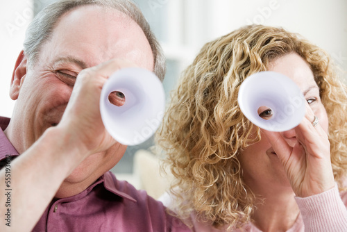 View of a mature couple peeping through rolled up paper. photo