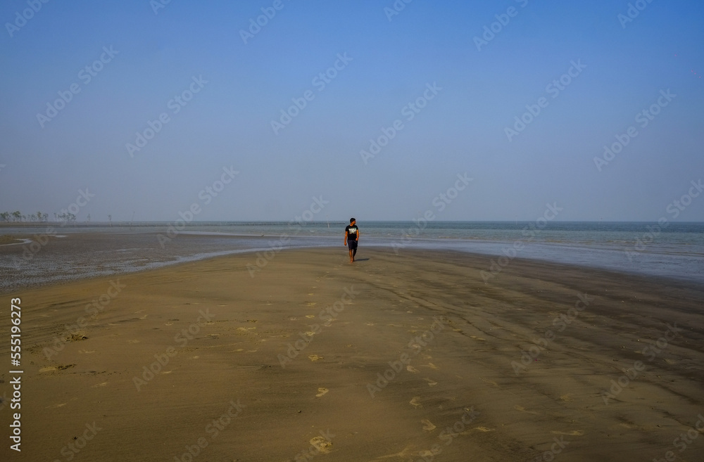south asian young boy walking on the beach