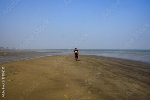 south asian young boy walking alone on the beach