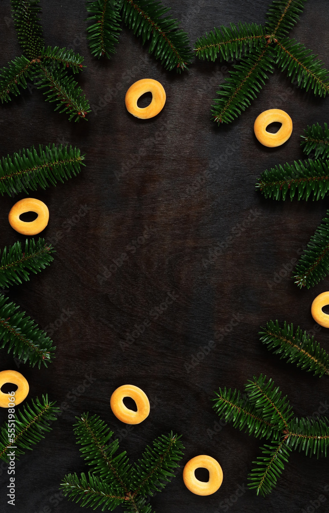 Branches of Korean fir on the background of a wooden table, top view. Christmas background with coniferous tree branches and bagels Branches of Korean fir on the background of a wooden table, top view. Christmas background with coniferous tree branches and bagels