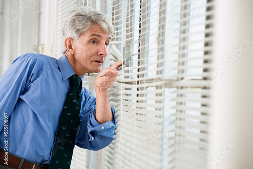A business man looking out from his office window.