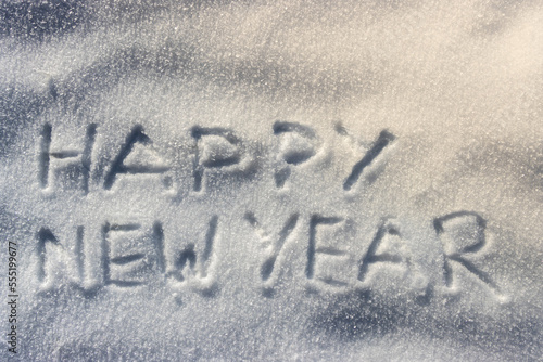 "Happy new year" written on fresh white snow during a sunny winter day