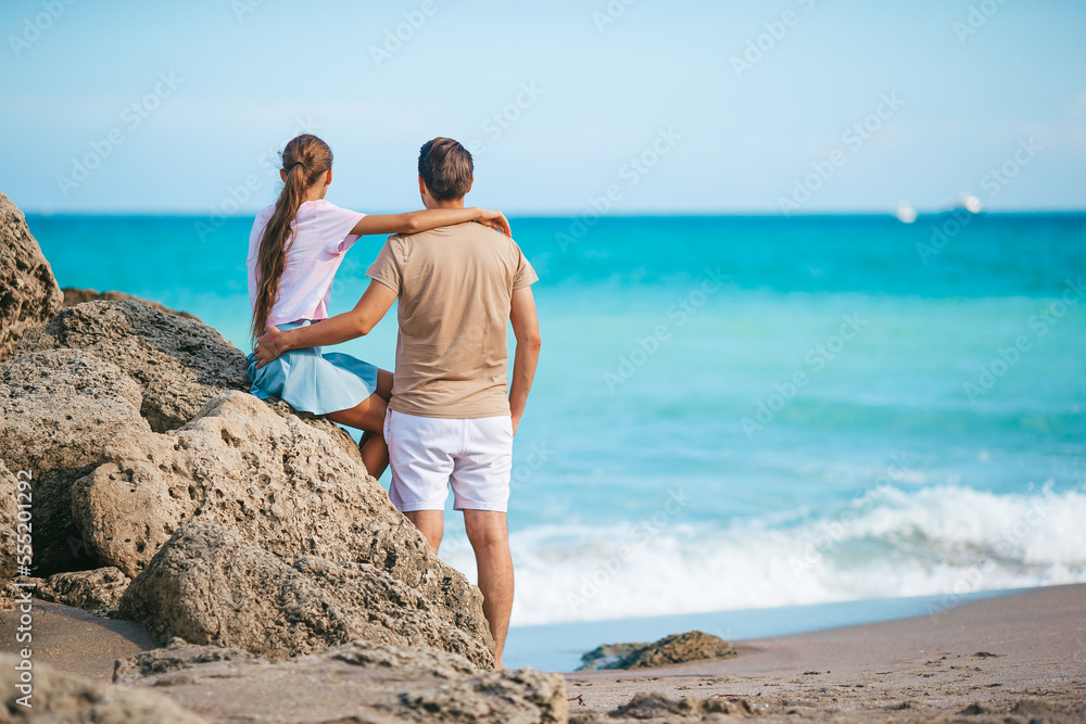 Family of young father and cute daughter enjoy the view of the sea on the beach Family of young father and cute daughter enjoy the view of the sea on the beach