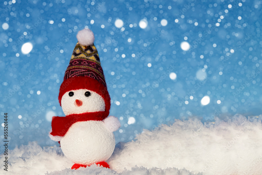 Fototapeta premium The snowman is standing in the snow and it is snowing. Festive Christmas card.