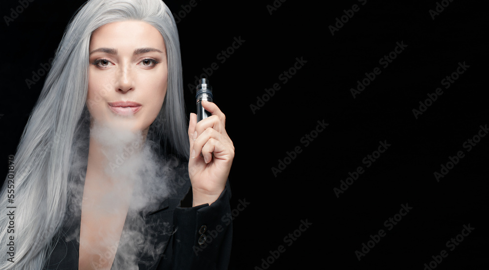Sensual gray haired woman using electronic cigarette. Beauty model woman with a vaping device blowing a white cloud of smoke. Horizontal portrait isolated on black background with copy space Sensual gray haired woman using electronic cigarette. Beauty model woman with a vaping device blowing a white cloud of smoke. Horizontal portrait isolated on black background with copy space