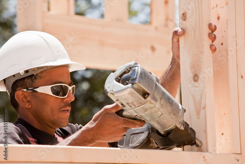 Carpenter using a nail gun at a construction site photo