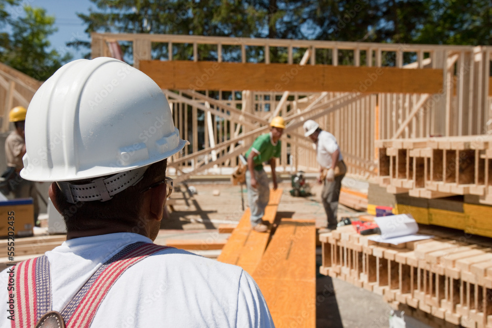 Carpenters working on a lamination beam at a construction site Carpenters working on a lamination beam at a construction site
