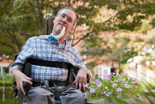 Man with Duchenne muscular dystrophy sitting in a wheelchair with a breathing ventilator photo