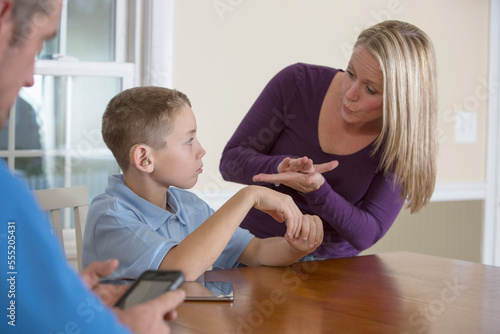 Mother communicating with son in American Sign Language 'School' at home