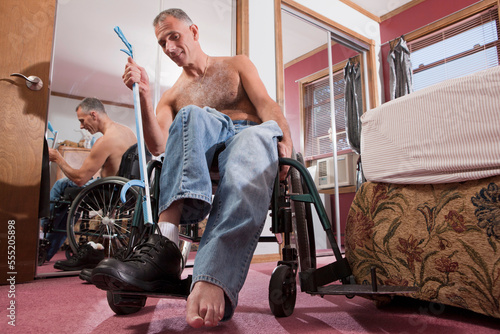 Man with spinal cord injury untying his shoes with an extension tool photo