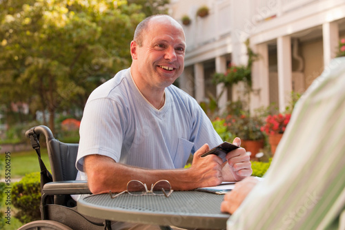 Businessman with Friedreich's Ataxia text messaging on a mobile phone with hand degeneration