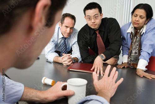View of businesspeople conversing about drugs in an office.
