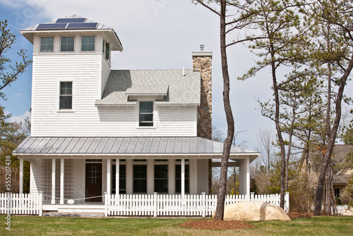 Green Technology Home with wrap-around porch, light reflective roof and solar electric power panels photo