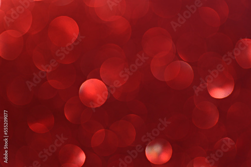Red glitters with bokeh effect and selective focus. Festive background with bright ruby lights. Christmas mood concept. Copy space for text.