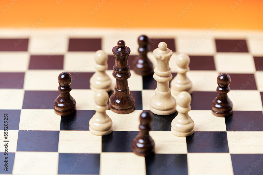 Chess pieces on a chessboard on an orange background Chess pieces on a chessboard on an orange background