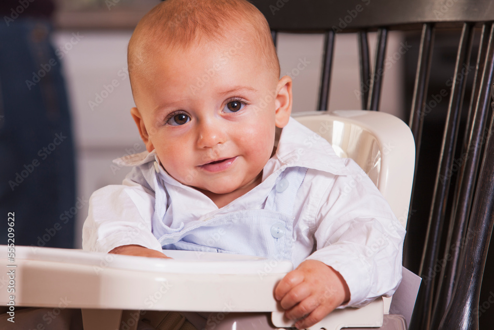 Smiling baby boy sitting in a booster seat Smiling baby boy sitting in a booster seat