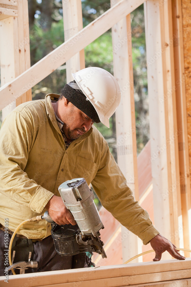 Carpenter using a nail gun on studs Carpenter using a nail gun on studs