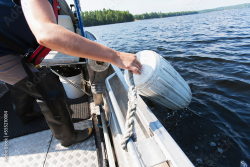 Public works engineer on service boat pulling boat fender to take public water samples from reservoir