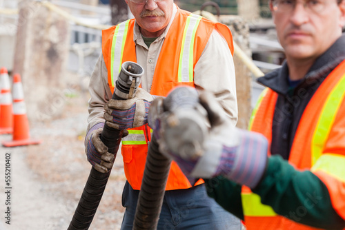 Environmental engineers examining hose coupling for toxic waste petroleum cleanup