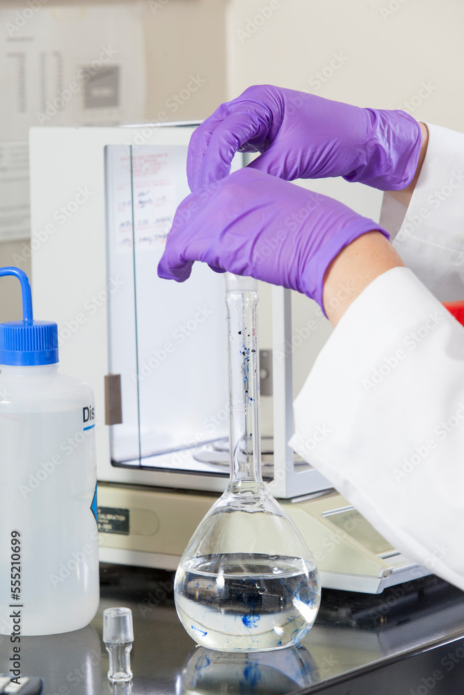 Laboratory scientist adding a precision amount of indigo into water sample flask Laboratory scientist adding a precision amount of indigo into water sample flask