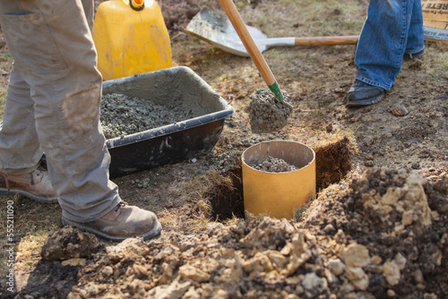 Hispanic carpenter adding cement to deck footing tube