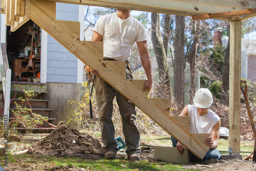 Hispanic carpenters installing stair stringer on house deck construction photo