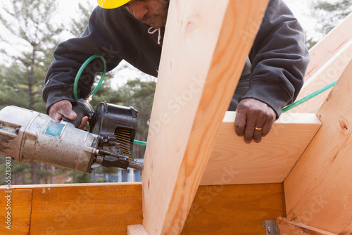 Carpenter with a nail gun on rafter braces photo