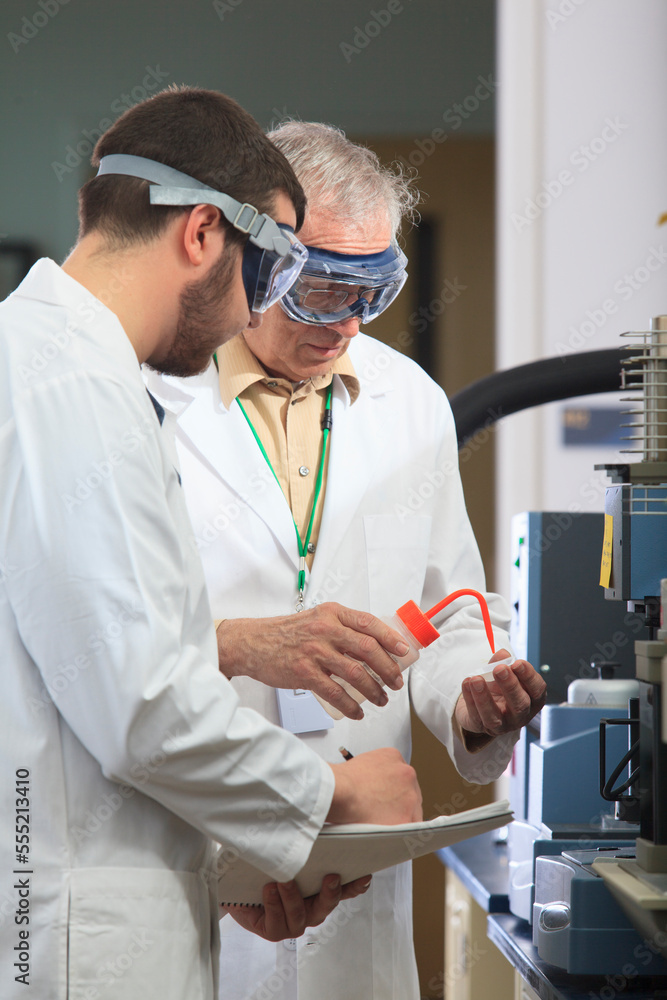 Professor working with engineering student adding ethanol to sample ...