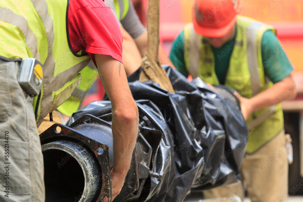 Construction workers guiding water main into place Construction workers guiding water main into place