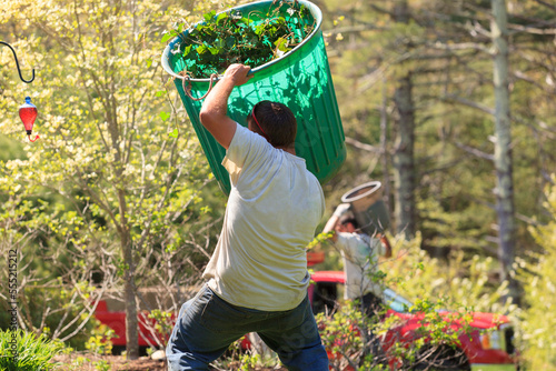 Landscapers carrying bins of weeds