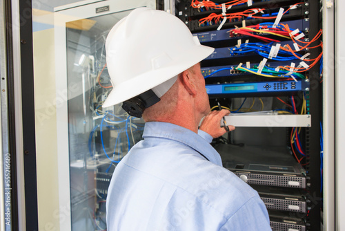 Engineer at electric power plant control room looking at servers and switches photo