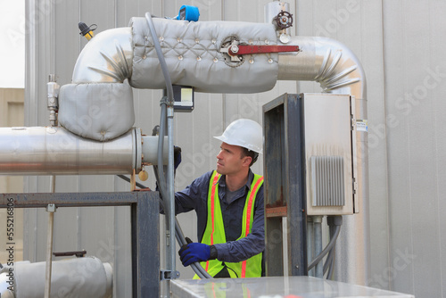 Industrial engineer reading a transducer display on insulated high pressure pipe in a power plant photo