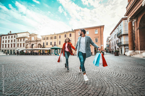 Εκτύπωση καμβά Happy beautiful young couple holding shopping bags walking on city street - Two
